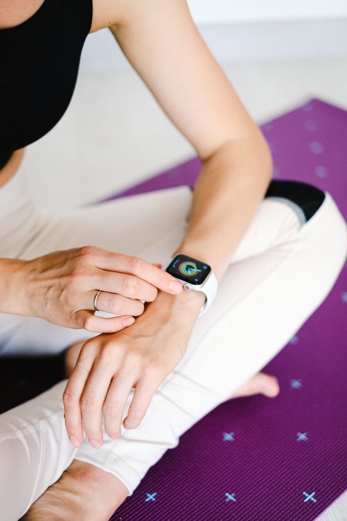 Person on yoga mat checking Apple Watch during fitness session